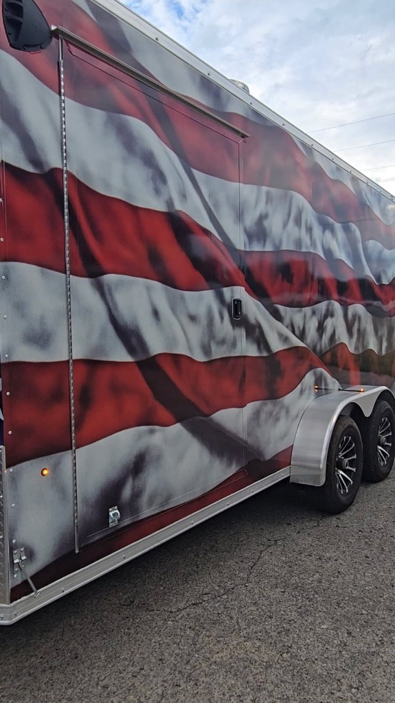 Finished enclosed trailer wrap — waving American flag stripes on the side, printed by 580 Graphics